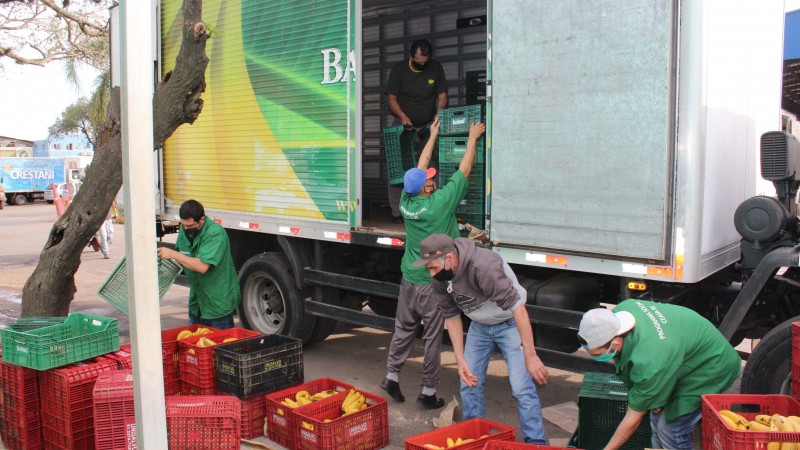 Homens carregando um caminhão baú com caixas de hortigranjeiros